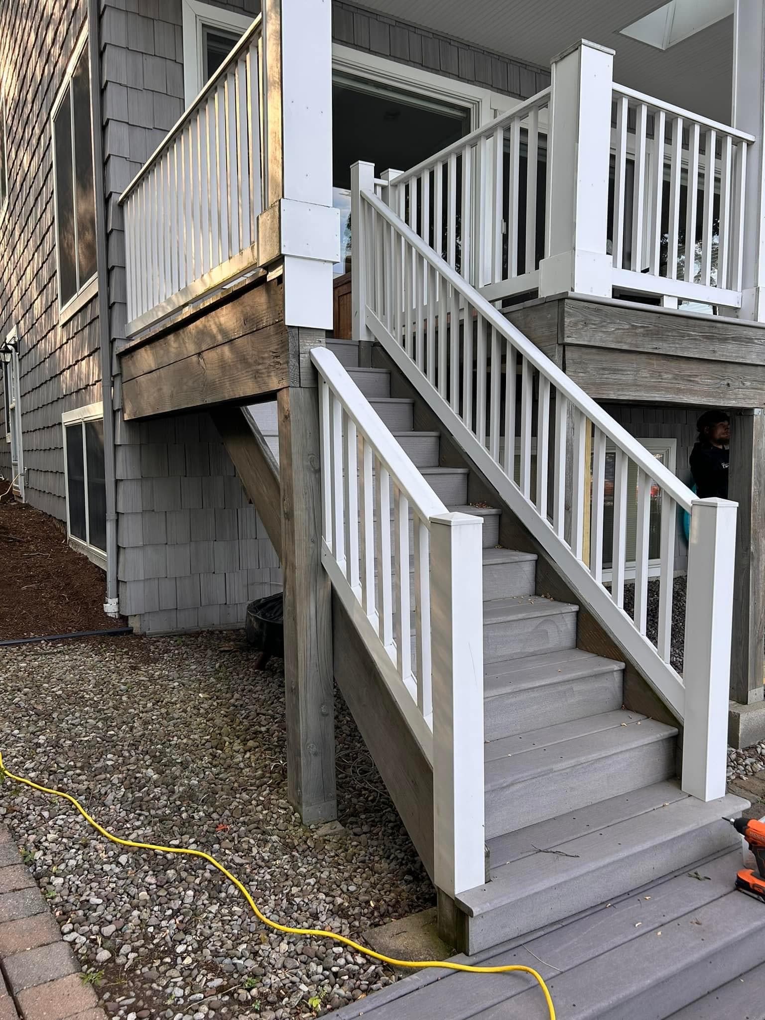 Exterior wooden staircase with white railings leading to second-story porch