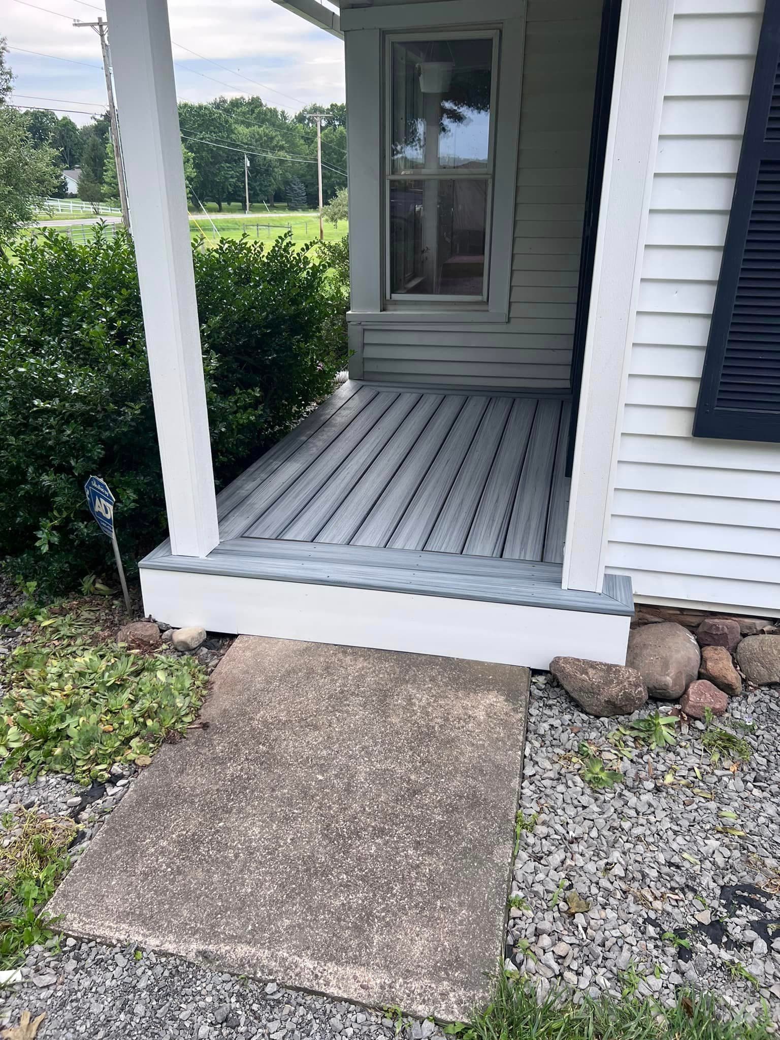 Gray composite deck porch with white columns and green siding