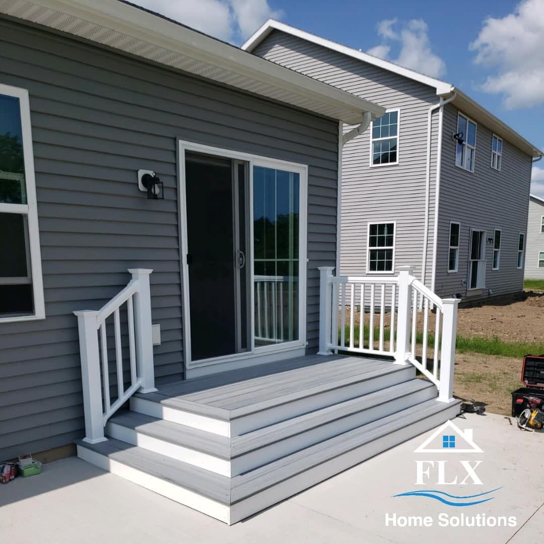 Custom deck with gray composite decking and white railings leading to back door