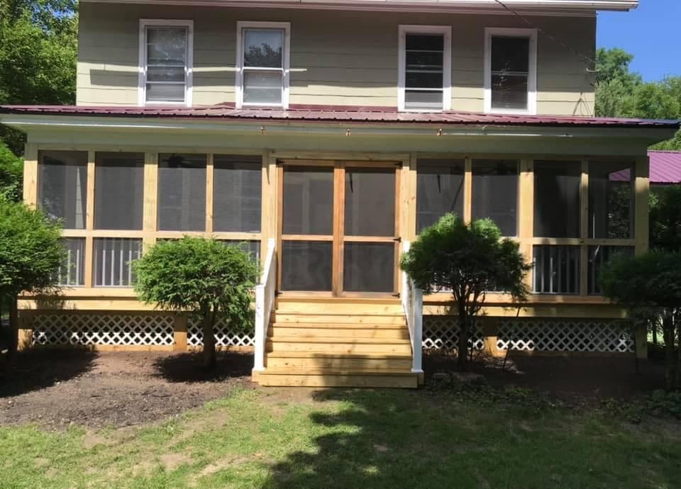 Two-story home with newly built screened porch featuring fresh lumber framing and central staircase