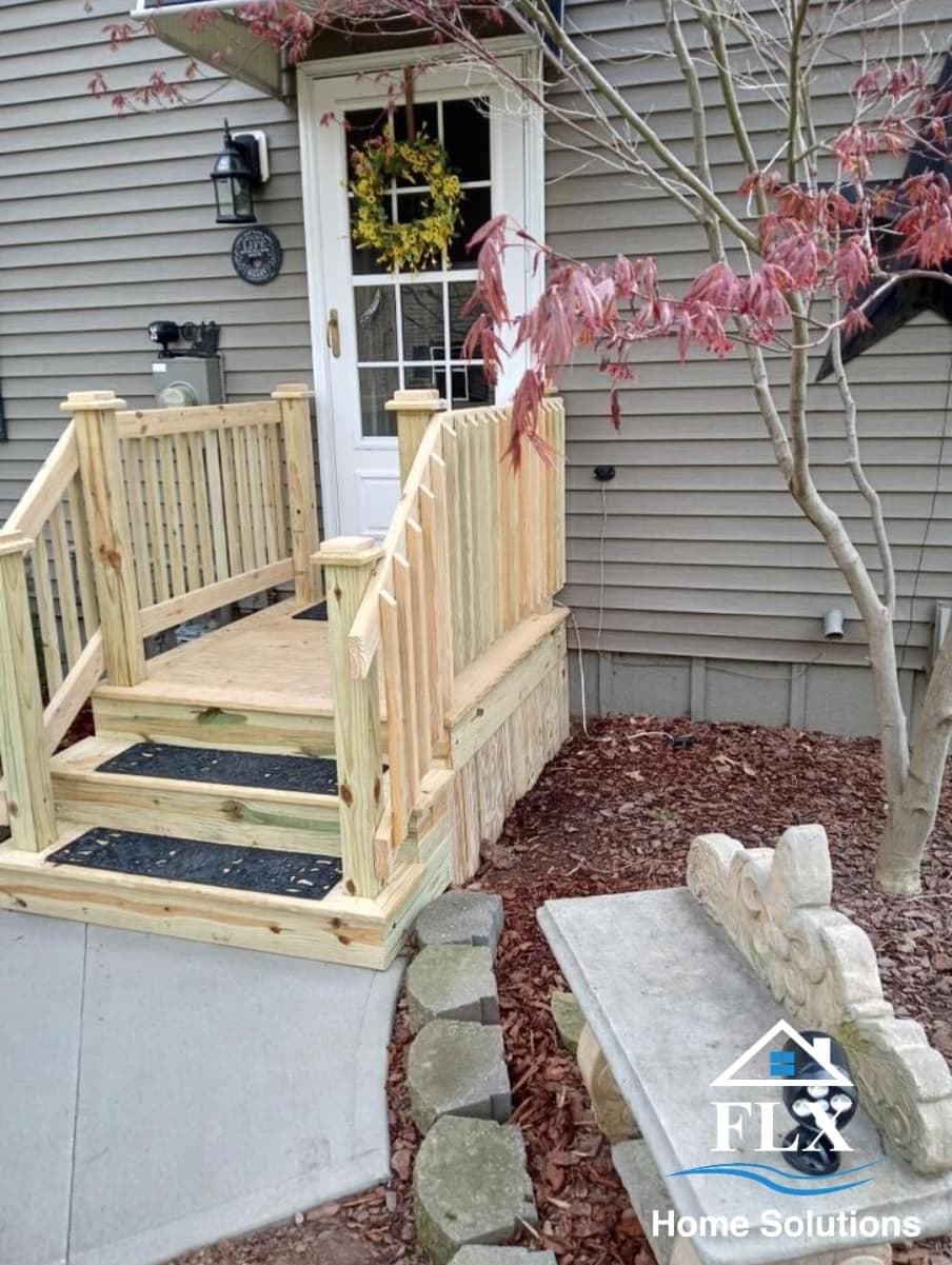 Wooden porch with railings and steps leading to white door with wreath