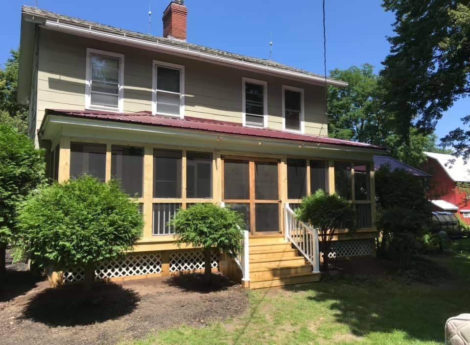 Two-story home with new screened porch addition featuring wooden deck and stairs
