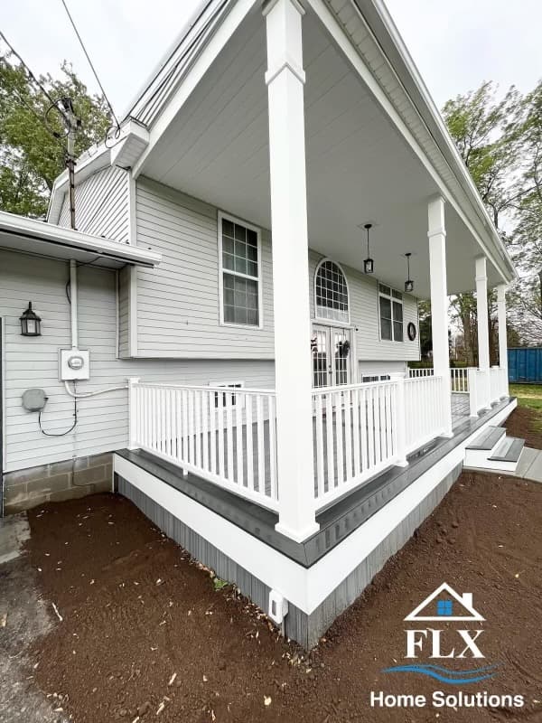 Covered porch with white columns, railings, and A-frame roof structure