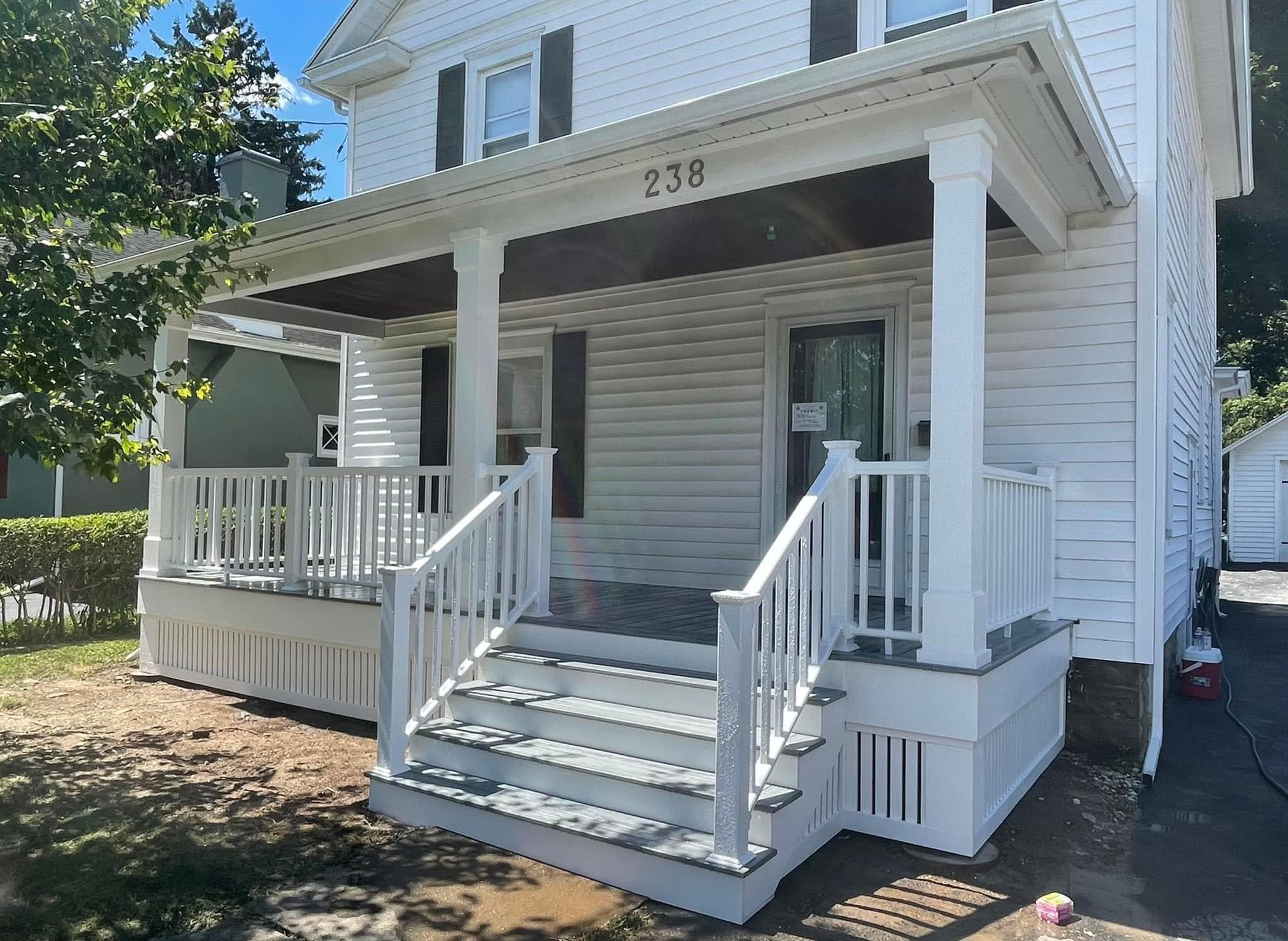 Front porch with white railings and steps at house number 238