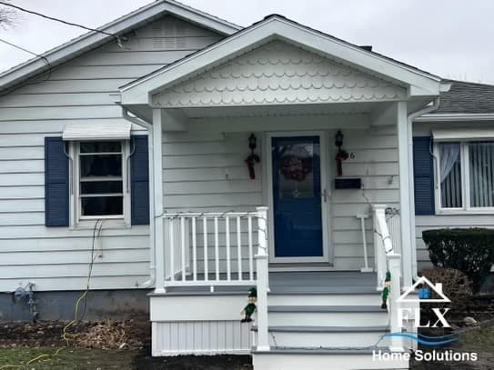 White horizontal siding home with covered front porch, blue door, and white railings