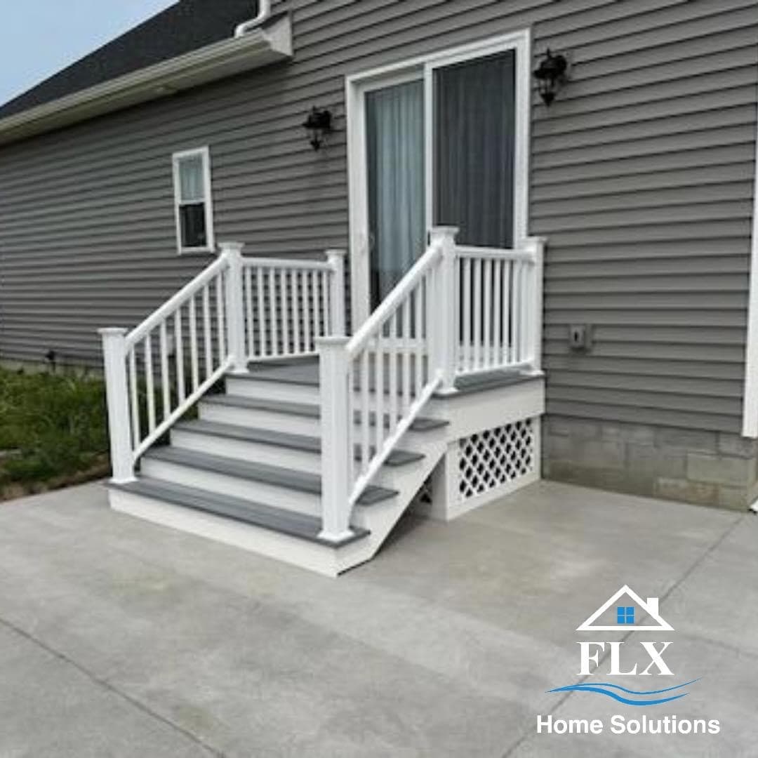 White porch stairs with railings leading to gray vinyl-sided house entrance