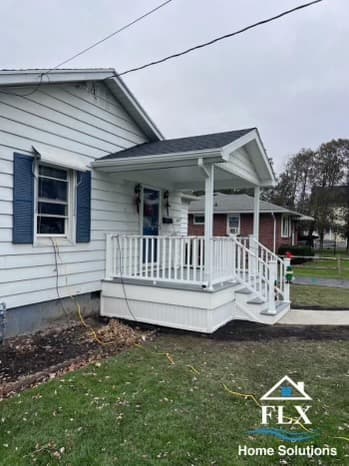 White porch with railings and steps on home with blue shutters