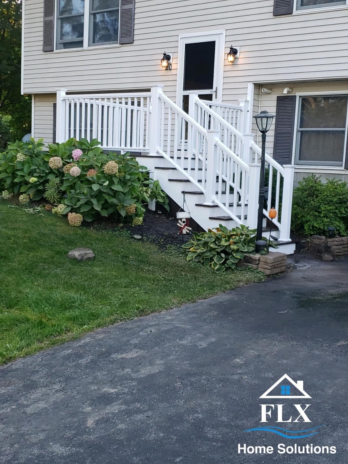 White porch with stairs, railings, and exterior lighting on beige house