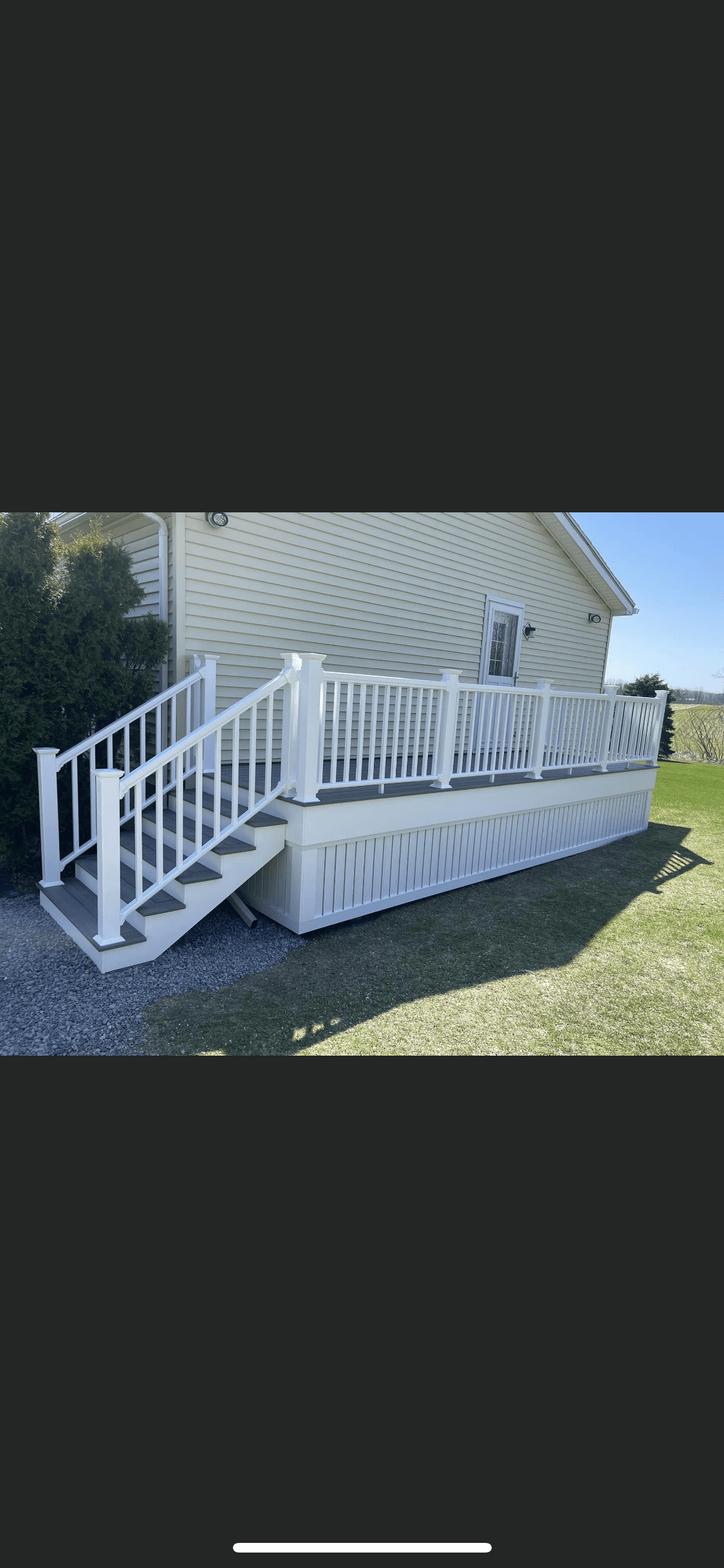 White deck with stairs and railings attached to tan vinyl siding house