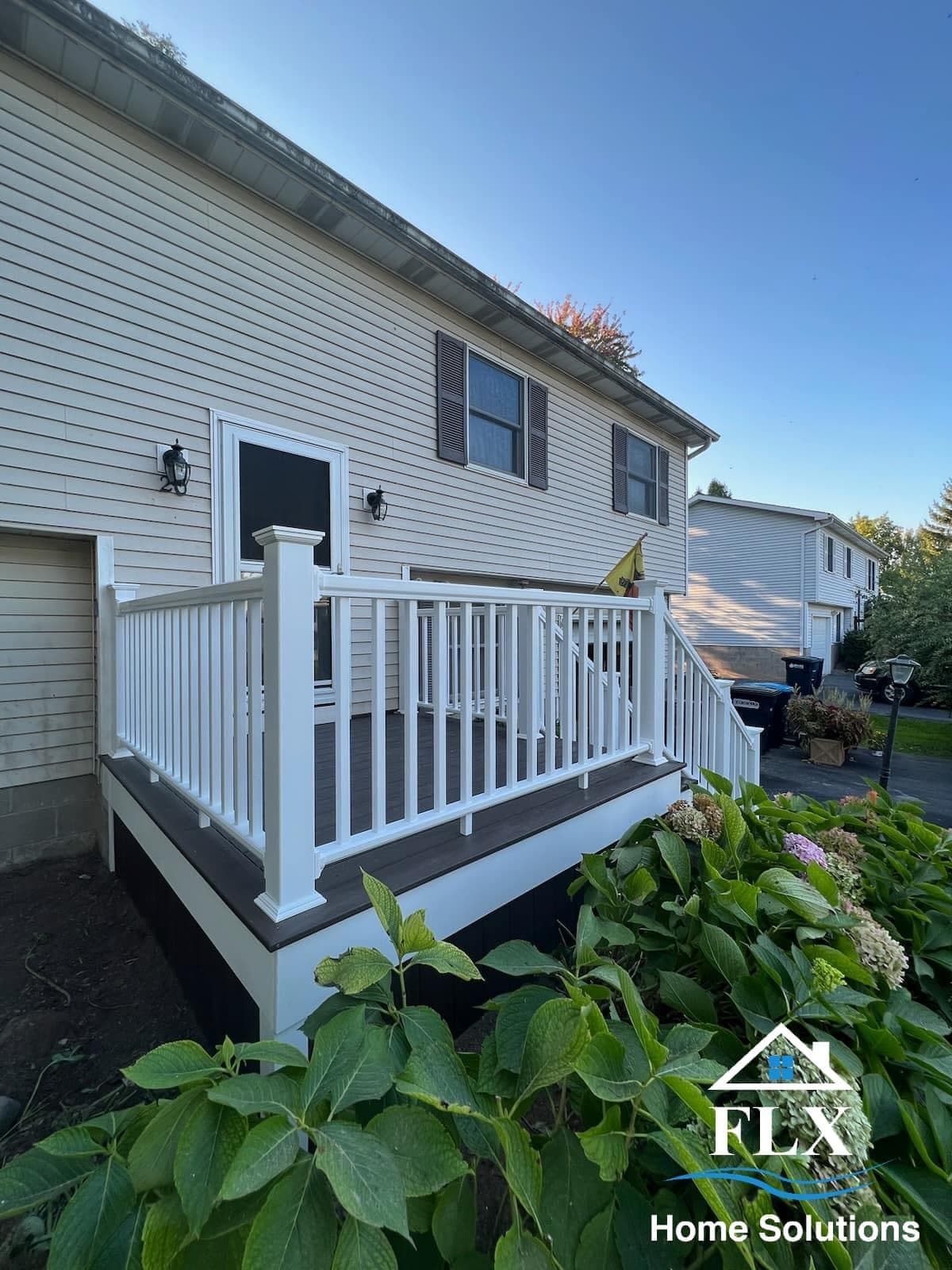 White-railed porch with black composite decking and black entry door