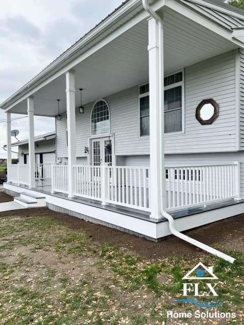 White raised ranch home with covered porch, white columns, and railings
