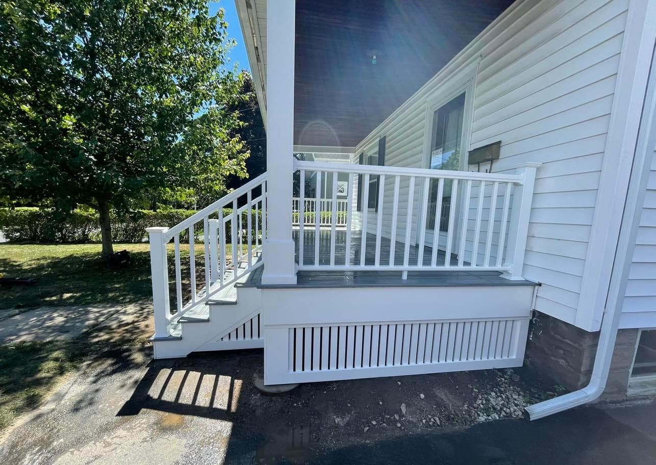 White wrap-around porch with vertical railings and lattice skirting