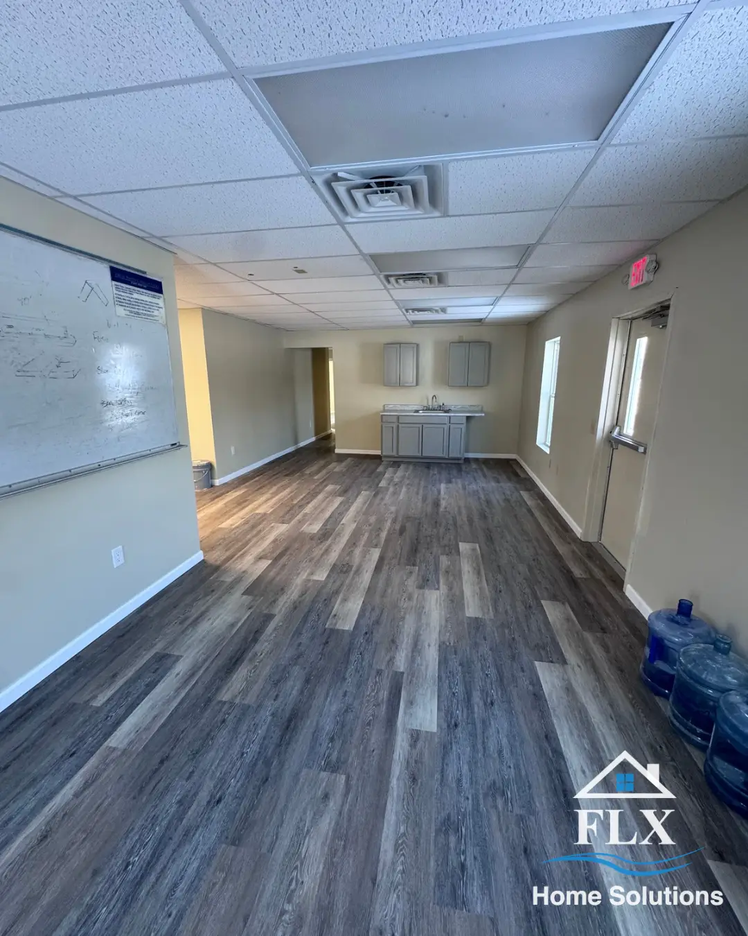 Renovated breakroom with vinyl plank flooring, whiteboard, and kitchenette area