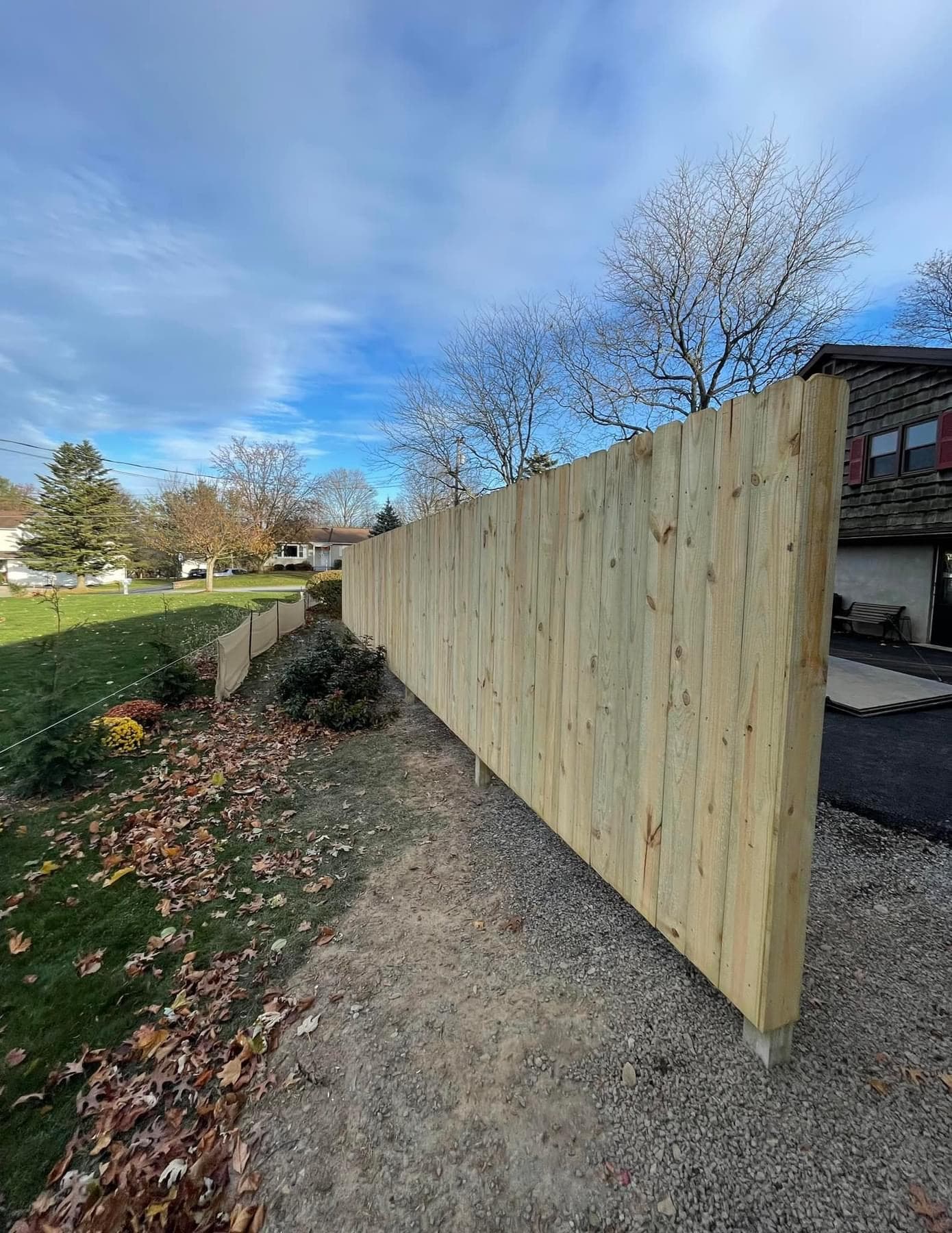 Tall wooden privacy fence installed along residential driveway
