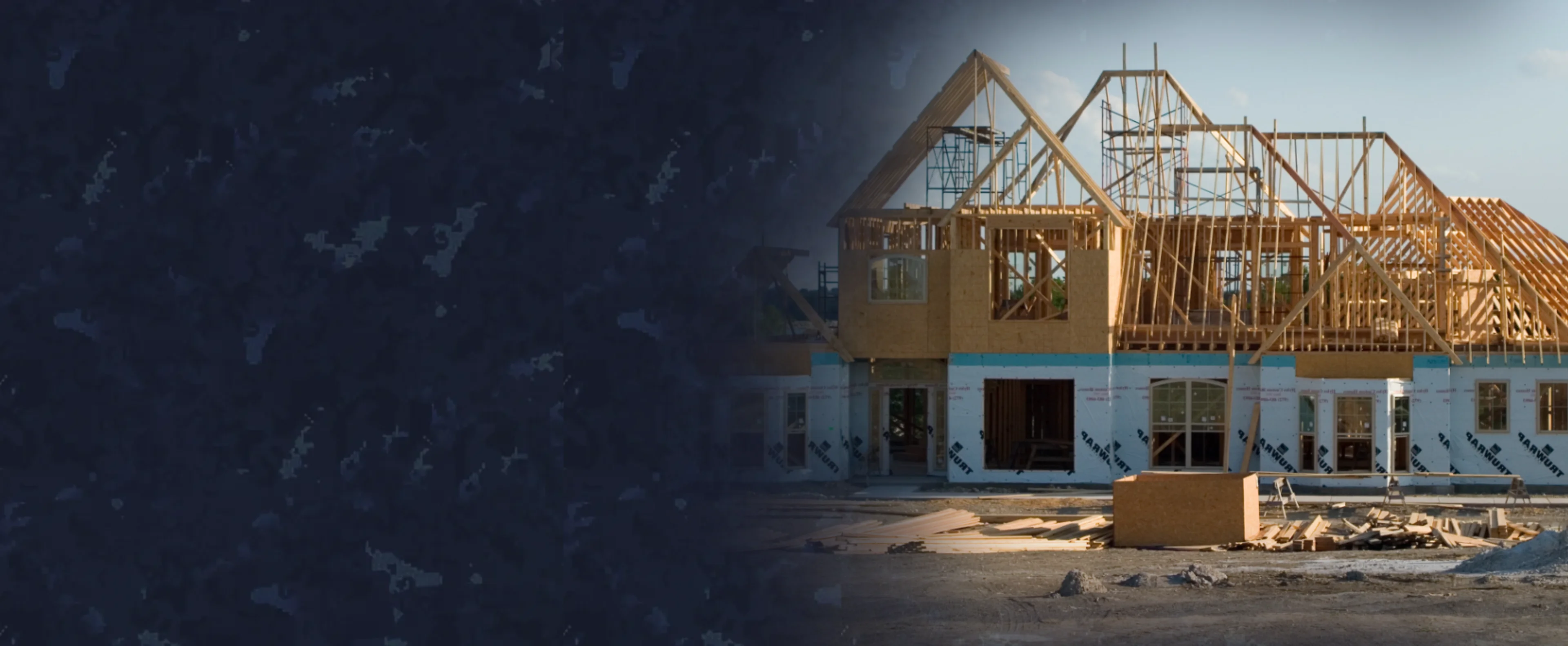 Custom home under construction with wooden framing and blue house wrap